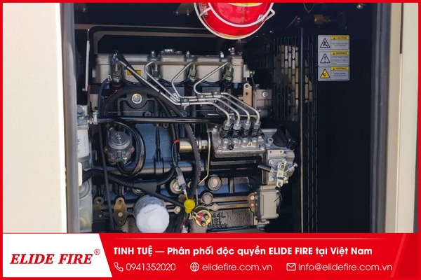 Đồ hoạ/sơ đồ: mặt cắt khoang máy phát điện diesel dạng minh hoạ kỹ thuật, đánh dấu 3 điểm nguy cơ cháy bằng icon ngọn lửa nhỏ tại cầu chì tủ điều khiển, đầu nối cáp điện và bộ lọc nhiên liệu, kèm mũi tên chỉ khoảng cách 15-20cm tới vị trí lắp bóng chữa cháy.